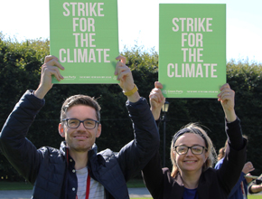 Two people hold green signs above head to promote climate change