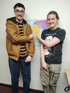 two students stood next to each other and a map