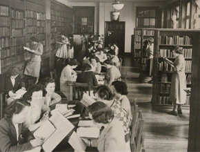 Old black and white photo of group of people in a library