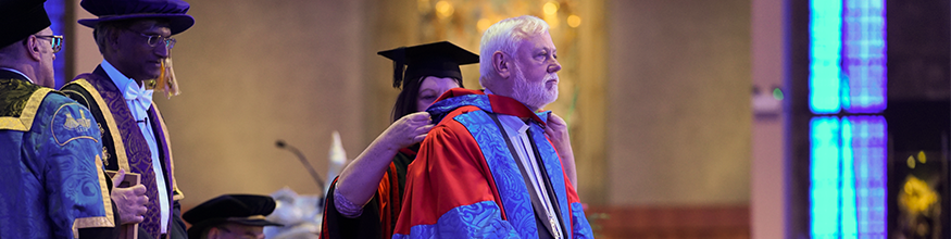 Bishop receive honorary award on the stage at graduation ceremony