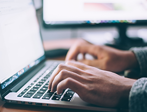 Person typing on laptop with a long sleeve shirt on