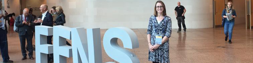 Lady standing next to letters saying FENS