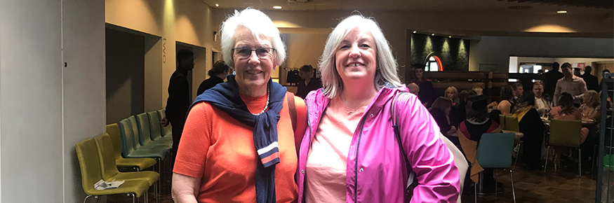 Two ladies smile at the camera while they are stood in Fresh Hope