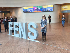 A lady stands next to a display of letters saying FENS