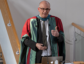 academic dressed in gown giving thumbs up