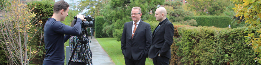 Photo of two academics being interviewed in front of a video camera