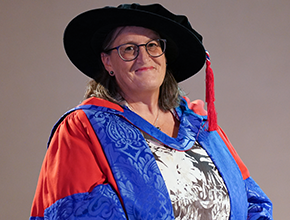 Chancellor Monica Grady smiles to camera wearing cap and gown