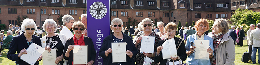 Group of alumni smile for photo holding their certificates