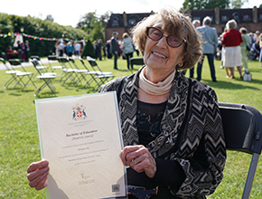 Barbara Fry smiles at camera and holds up her certificate
