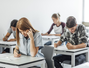 A group of students sitting at individual desks taking a written exam