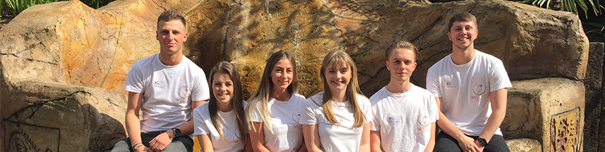 Six students wearing white t-shirts sat on a rock