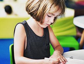 child sitting at desk writing