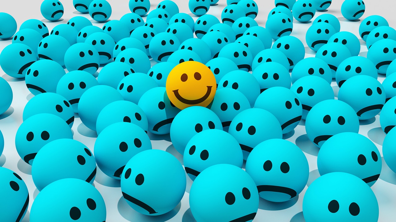 yellow smiley surrounded by sad blue emoticons