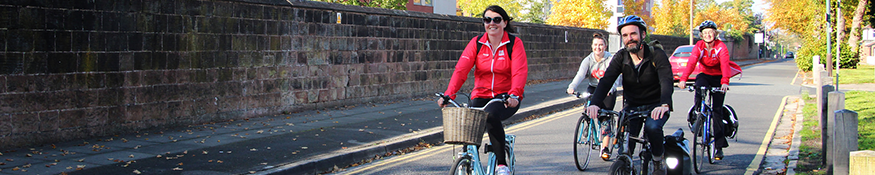 Three people cycling on the road next to a Hope building