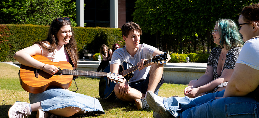 Liverpool Hope students playing guitar on the lawn