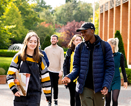 Group of students walking outside, two students are more in focus talking to each other